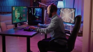 Gamer playing fast paced space shooter simulation screaming victorious at the computer screen after winning difficult level. Caucasian man celebrating victory in internet multiplayer action game.