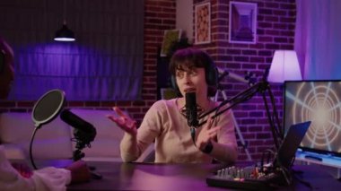 Ev sahibi stüdyodaki gece yarısı eğlence programında Afrikalı Amerikalı şarkıcıyla online radyo sunucusu röportajının portresi. Profesyonel ses donanımı kullanan sıradan bir kadın mülakatçısı..