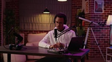 Ev kayıt stüdyosundaki dinleyicilerin sorularını cevaplarken kameraya kendinden emin gülümseyen insan portresi. Afro-amerikan çevrimiçi radyo sunucusu dizüstü bilgisayardan hayran mektupları okuyor.