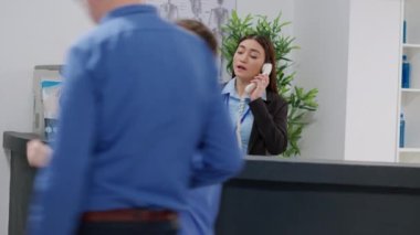 Asian receptionist and medical assistant working with checkup papers to help patients, doing healthcare appointments with insurance. Diverse team doing registration work at hospital reception desk.