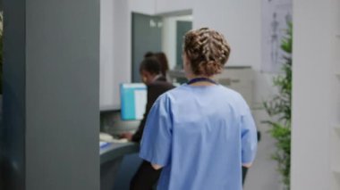 Multiethnic medical staff analyzing appointment forms and reports at hospital reception desk in health center. Specialists working at registration counter for checkup visits in clinic lobby.
