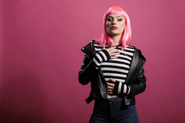 Portrait of sensual glamour girl posing in front of camera, wearing trendy leather jacket to feel stylish and carefree. Female punk rocker with pretty fashion style, having fun.