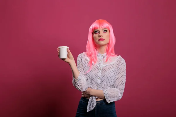 Caucasian woman doing eye roll gesture and holding cup of coffee, feeling displeased and indifferent in front of camera. Having annoyed attitude and feeling discontent, uninterested.