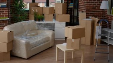 Empty apartment flat full of moving unpacked cardboard boxes, storage packages in living room. Relocation concept in new real estate property, furniture in carton containers with no people.
