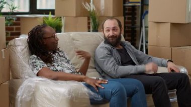 Evdeki kutuları taşıdıktan sonra ara verip koltukta dinlenen ve ev yatırımlarını kutlayan bitkin hayat arkadaşları. Yeni gayrimenkul dekorasyonundan dolayı yorgun hissediyorum..