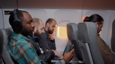 Afrika kökenli Amerikalı yolcu cep telefonuyla internete girip uçakla inmeyi bekliyor. Günbatımında turistlerle uçmak, akıllı telefon kullanmak. El kamerasıyla..