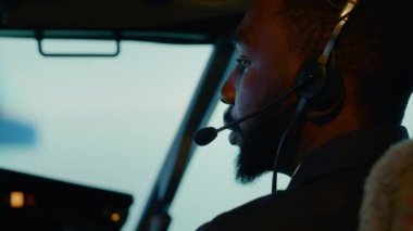 African american copilot preparing to takeoff and fly plane, using dashboard command in cockpit. Windscreen navigation and control panel buttons to travel with airplane. Close up.
