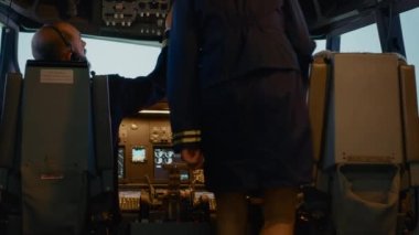 Captain and woman copilot in cockpit preparing to fly airplane, using dashboard command buttons to fix altitude and longitude control to takeoff. Aerial navigation with radar compass.