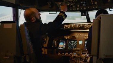 Çeşitli kaptanlar ve yardımcı pilotlar uçak uçurmak için güç düğmelerini değiştiriyor, motor komutuyla kalkışa hazırlanıyorlar. Hava yolu taşımacılığı için kontrol paneli ve kokpit göstergesi kullanılıyor. El kamerasıyla..