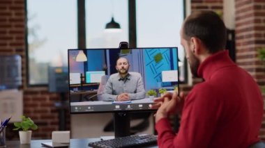 Şirket çalışanı ofiste uzaktan konuşma yapmak için çevrimiçi video konferansını kullanıyor. Erkek işçi video telekonferansında danışmanla konuşuyor, bilgisayar brifingine katılıyor..