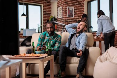 Frustrated men playing video games online and losing at home, feeling sad about lost competition. Group of friends enjoying fun leisure activity with alcohol beer bottles and food.