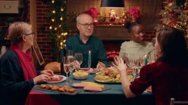 Senior person talking praising daughter about traditional home cooked food at Christmas dinner table. Festive family members celebrating winter season holiday while enjoying time together at home.