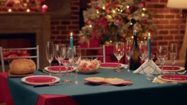 Empty interior of festive traditional Christmas dinner table with authentic decorative cutlery and dinnerware. Cozy and ornate looking living room with seasonal and positive style with nobody in it.