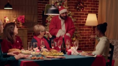 Confident man disguised as Santa showing up with gifts for everybody at winter holiday celebration. Santa Claus looking person surprising everybody at Christmas dinner when he shows up with presents.