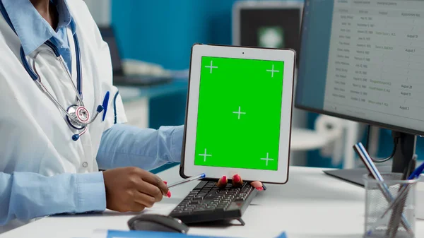 Female doctor holding tablet with greenscreen at checkup with paralyzed patient. Using blank copyspace background with isolated display and chromakey mockup template. Close up.