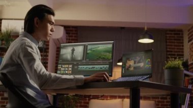 Asian videographer working with video editor and montage on post production software to create movie footage. Edit color grading and visual effects on multimedia film. Handheld shot.