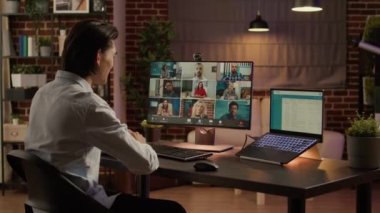 Businessman attending videocall meeting on computer, talking to group of colleagues on remote teleconference chat. Videoconference conversation for telecommunications. Handheld shot.