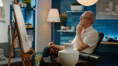 Beyaz tuval üzerine sanatsal şaheser çizmek için profesyonel beceriler kullanarak vazo esinlenmeye çalışan yaşlı bir sanatçı. Sanat ve zanaat hobisi için özgün tasarım çizimi.