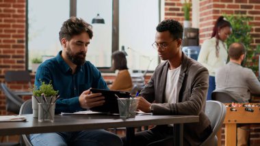 Business men analyzing charts data on digital tablet, doign teamwork collaboration to plan research presentation with graphs on paperwork. Analyzing report information on documents. Tripod shot.