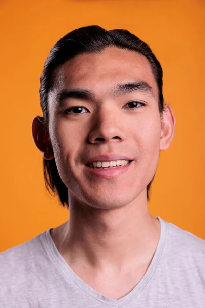 Young cheerful smiling asian man portrait closeup, guy looking at camera. Carefree teenager with positive facial expression close view, attractive person face with joyful emotion