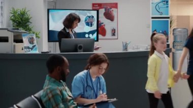 Diverse group of patients asking for help at hospital reception desk, sitting in waiting area lobby. Mother with child, senior man and asian patient having appointment at busy medical clinic.