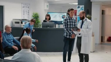 Asyalı hasta doktorla teşhis ve tedavi hakkında konuşuyor, bekleme odasında hastane resepsiyonunda konuşuyor. Sağlık hizmetleri danışmanlığı randevusu.