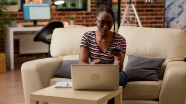 Young woman using credit card to shop online on website, buying clothes from retail store. Shopaholic adult making money payment and electronic transaction, doing purchase on sale.