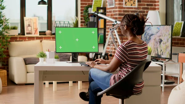 Company employee using greenscreen on computer and doing remote work, looking at monitor. Businesswoman working remotely with isolated chroma key template, blank mockup background.