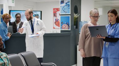 Hastane resepsiyonunda kıdemli bir hastaya danışmanlık yapıyor. Hastalık teşhisi ve sağlık tedavisi için dizüstü bilgisayara bakıyor. Bekleme odasında farklı kadınlar var..