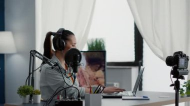 Internet live radio show host typing on computer while talking to audience. Famous digital content creator chatting with public on live chat while speaking on modern microphone.