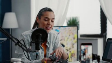 Tech enthusiast reviewing wireless mouse while presenting specifications to public. Attractive social media star doing recommendation video for electronic peripheral while sitting at home studio desk.