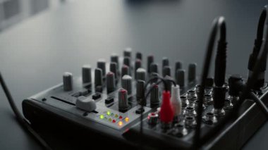 DJ mixer console with knobs and equalizer standing on home studio desk. Professional audio sound station electronic controller in living room video recording space. Close up
