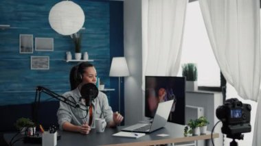 Famous internet podcaster checking show subject list on laptop while speaking to audience. Social media popular influencer with headphones talking to public about last worldwide events.