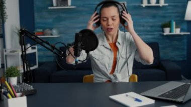 Popüler internet yayını etkileyicisi kulaklık takıyor ve günlük vlog kaydına başlıyor. Sosyal medya yıldızı oturma odasında podcast videosu çekerken stüdyo masasında oturuyor. Stüdyo çekimi