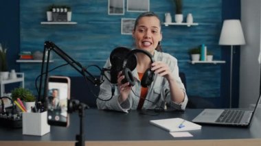 Popüler teknoloji meraklısı, evdeki oturma odası stüdyosunda tavsiye videosu kaydederken modern kulaklıkları inceliyor. Ünlü sosyal medya etkileyicisi kulaklıklar için ürün tanıtım videosu yapıyor.