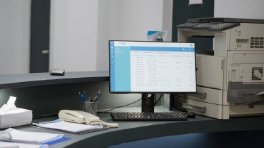Hospital reception counter with computer desktop to help with medical appointments and insurance forms. Empty registration desk to support checkup visits and do consultation reports.