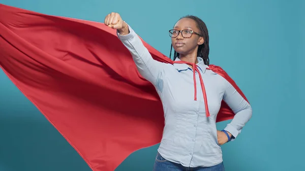 Portrait of superhero with flying red cape on camera, posing as action cartoon character with costume and cloak. Showing motivation and strength in studio, positive and powerful.