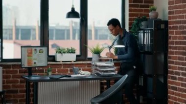 Terrified businessman in office hiding under table from scary zombies. Creepy bizarre looking brain-eating monsters with bloody wounds and scars chasing down doomsday survivor at workplace.