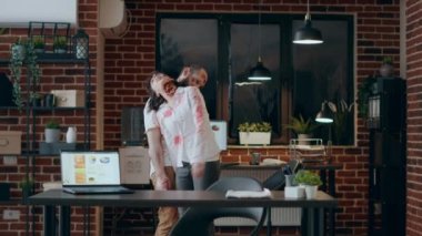 Scary crippled zombies wandering around office workspace. Mindless brain-eating walking dead corpses with bloody and deep scars roaming inside company space while growling and screaming creepy.