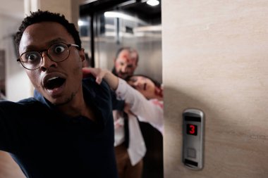 Frightened man running from evil zombies, trying to escape elevator from terrifying scary walkers. Brain eating monsters chasing and grabbing person, undead creepy walking dead corpses.