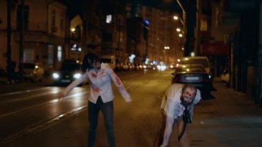 Scary brain-eating walking dead corpses looking frightening while prowling through city at night. Crippled looking brain-eating zombies with aggressive behaviour and bloody wounds looking for victims.