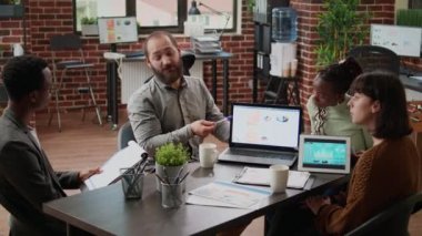 Multiethnic team of colleagues brainstorming ideas to do research and plan presentation with charts on papers. Business people working on data report, creating project analysis in boardroom.
