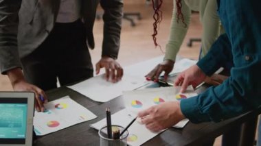 Business people analyzing charts information on documents, using files and papers to create report analysis. Colleagues working with diagrams and graphs to plan research. Close up.