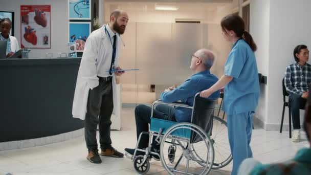 Male Doctor Meeting Old Patient Wheelchair Reception Lobby Having Conversation — Stockvideo