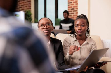 African american coworkers doing startup teamwork in startup office, meeting to work on company presentation with research information and report. Working on partnership collaboration.