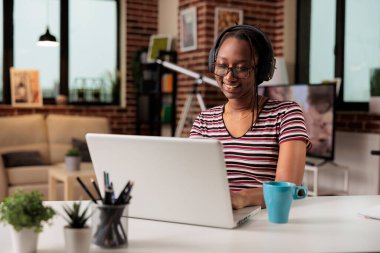 Smiling woman in headphones watching movie on streaming service on laptop, freelancer having break from work. Online film, entertainment, leisure activity, teenager in earphones relaxing