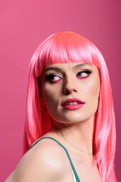 Portrait of beauty model with pink wig posing in front of camera, feeling confident and carefree in studio. Attractive sensual woman with glamour hairstyle showing elegant emotions.