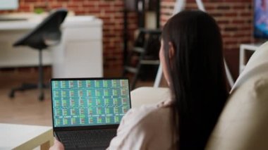 Focused woman analyzing market financial data charts while working remotely. Businesswoman doing remote work from home while looking over financial analytics report on laptop.