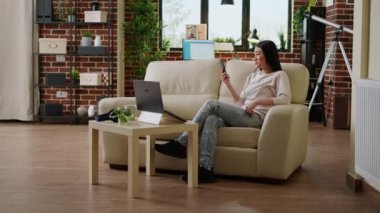 Happy asian freelancer on smartphone video call talking with client about job description. Smiling heartily woman discussing with work colleague on phone video call while working remotely.