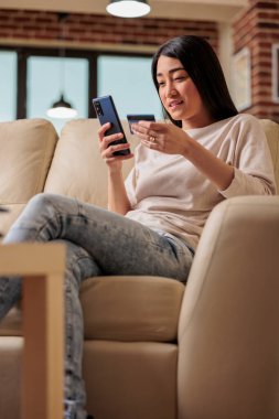İnternetten alışveriş yapan Asyalı bir kadın, kredi kartıyla alışveriş yapıyor, akıllı telefon kredisi kullanıyor, mutlu bir kadın internet üzerinden ödeme yapıyor, internet üzerinden ödeme yapıyor, müşteri Asya uygulama ödemesi yapıyor.